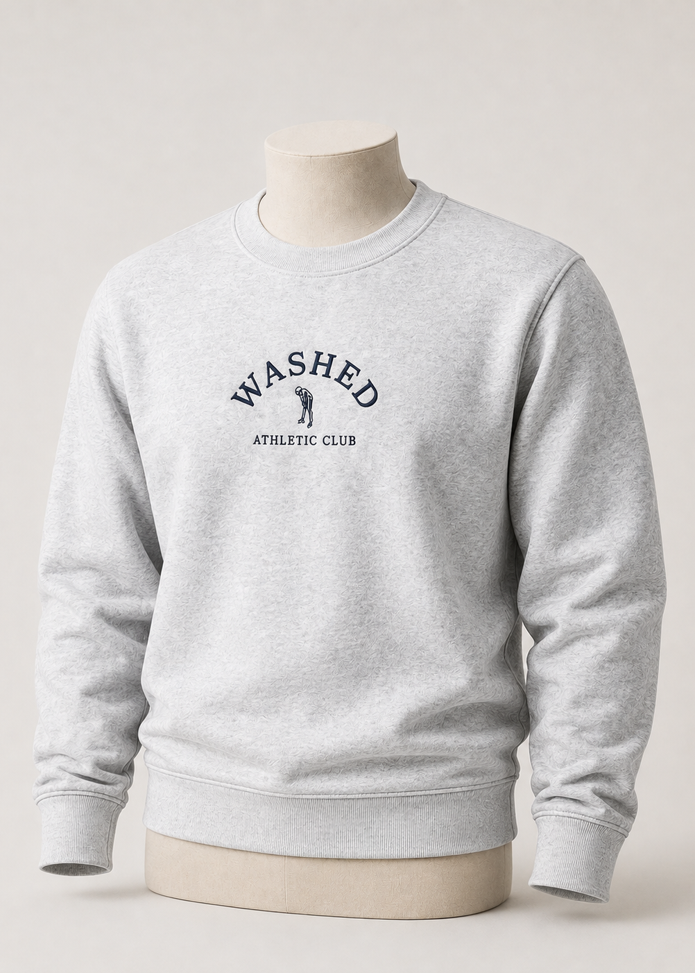 A light heather gray crewneck sweatshirt displayed on a beige mannequin torso against a neutral light gray background. The front of the sweatshirt features a dark navy blue graphic that reads 'WASHED ATHLETIC CLUB' with a small golfer silhouette.