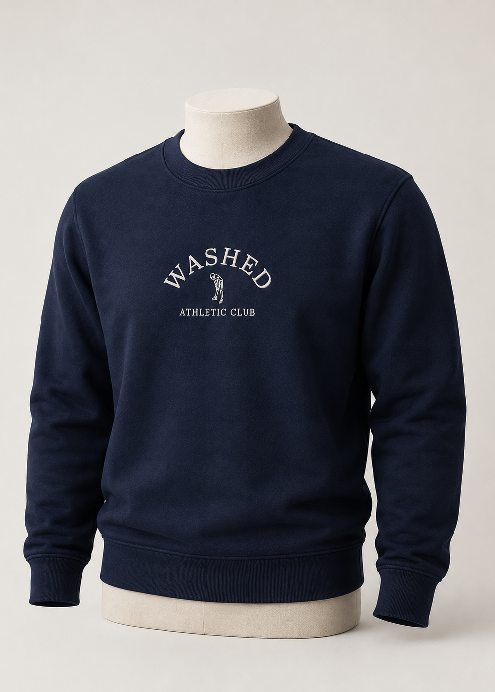 A navy blue crewneck sweatshirt displayed on a cream mannequin torso against a light gray studio background. The sweatshirt features a white printed graphic on the chest reading 'WASHED ATHLETIC CLUB' with a small golfer silhouette.