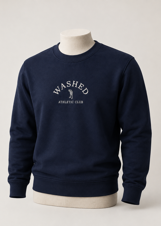 A navy blue crewneck sweatshirt displayed on a cream mannequin torso against a light gray studio background. The sweatshirt features a white printed graphic on the chest reading 'WASHED ATHLETIC CLUB' with a small golfer silhouette.